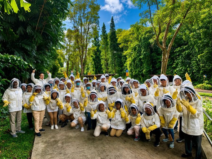 Edufarm group at a bee workshop at Bee Amazed Garden Singapore — participants in white beekeeping suits and yellow gloves