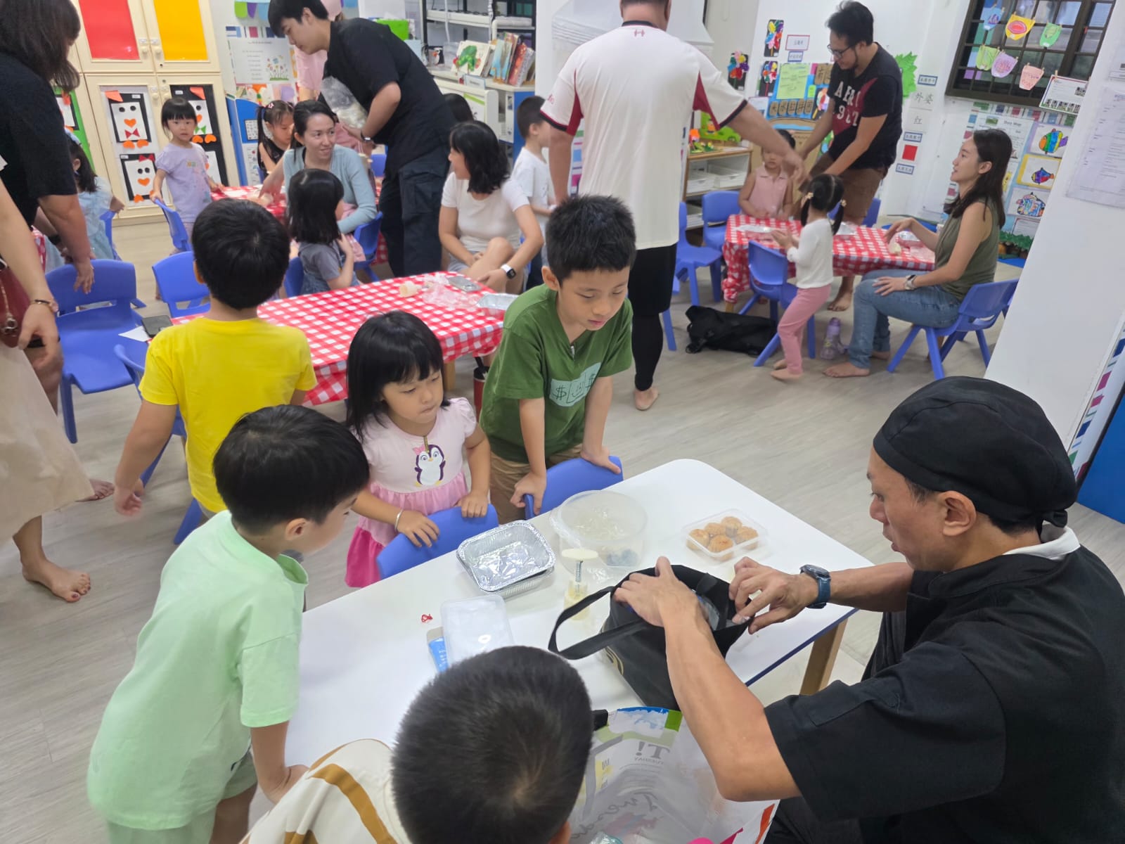 A busy Edufarm mooncake making workshop — children and parents making mooncakes at gingham-covered tables